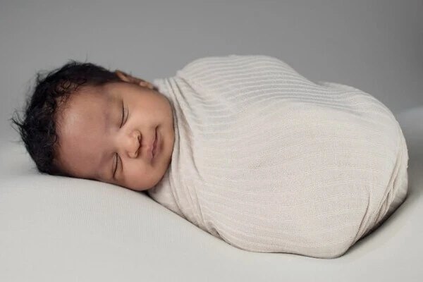 Sleeping newborn in white swaddle